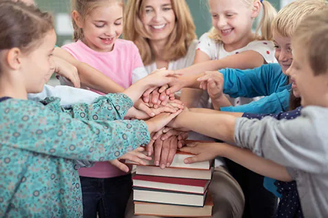 Kinder und Erwachsene legen ihre Hände als Gruppe aufeinander