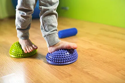 Kinderfüße balancieren auf zwei Noppenhalbkugeln